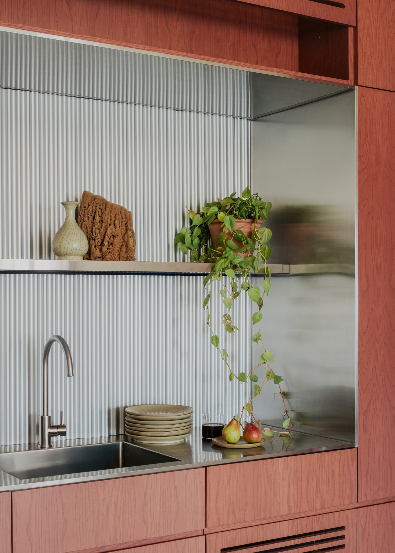 Close-up of warm timber cabinetry and curved wood panels against a raw concrete pillar.