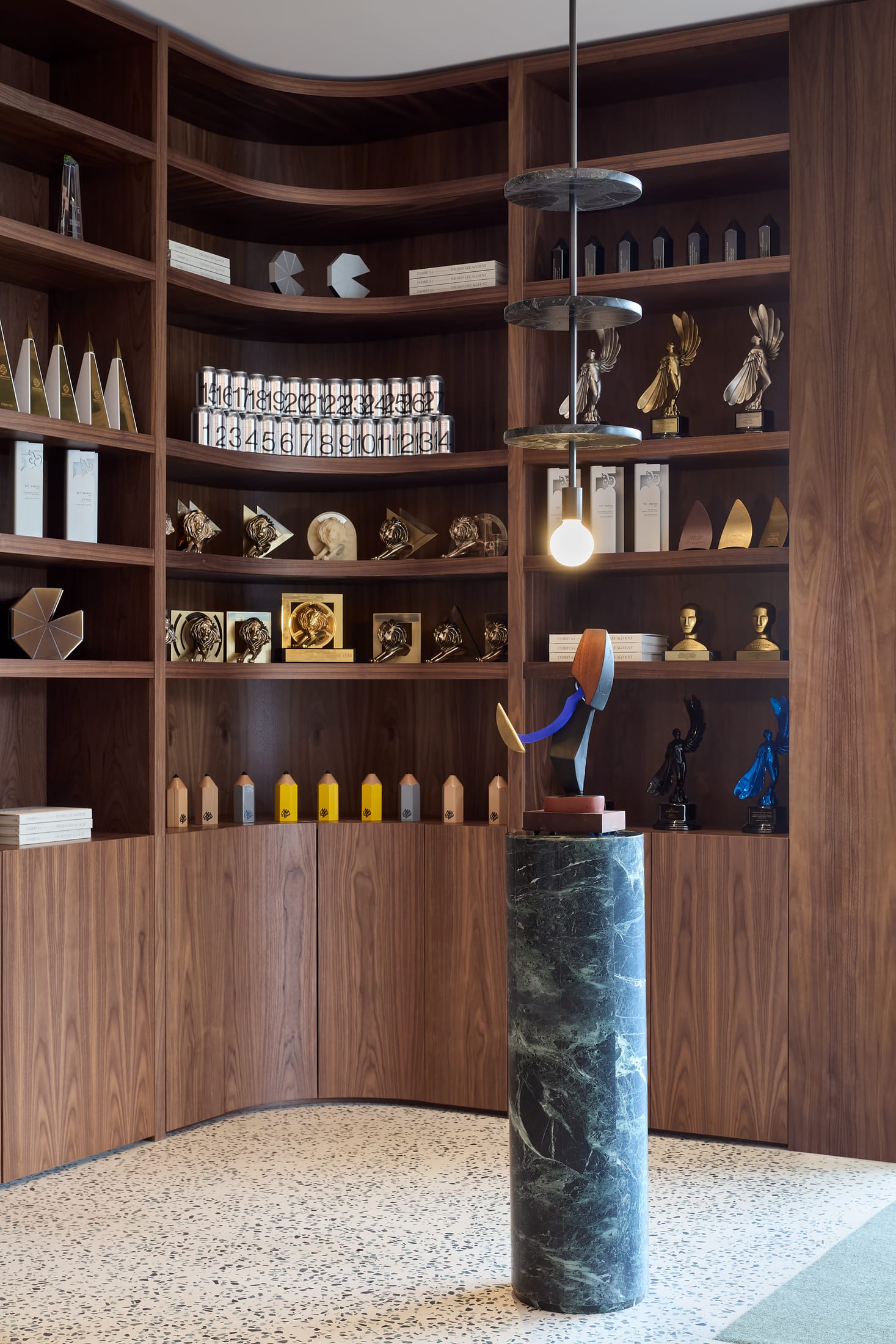 A modern kitchen area with stone countertops and warm lighting, looking out toward a brick screen.