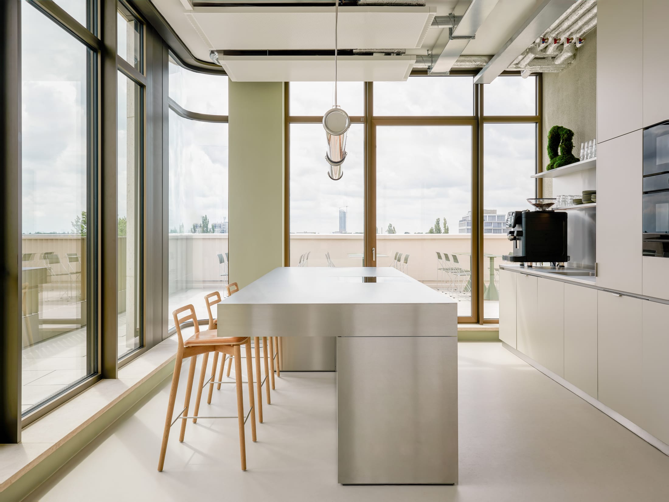 A modern, minimalist office kitchen with a sleek island and cabinetry.