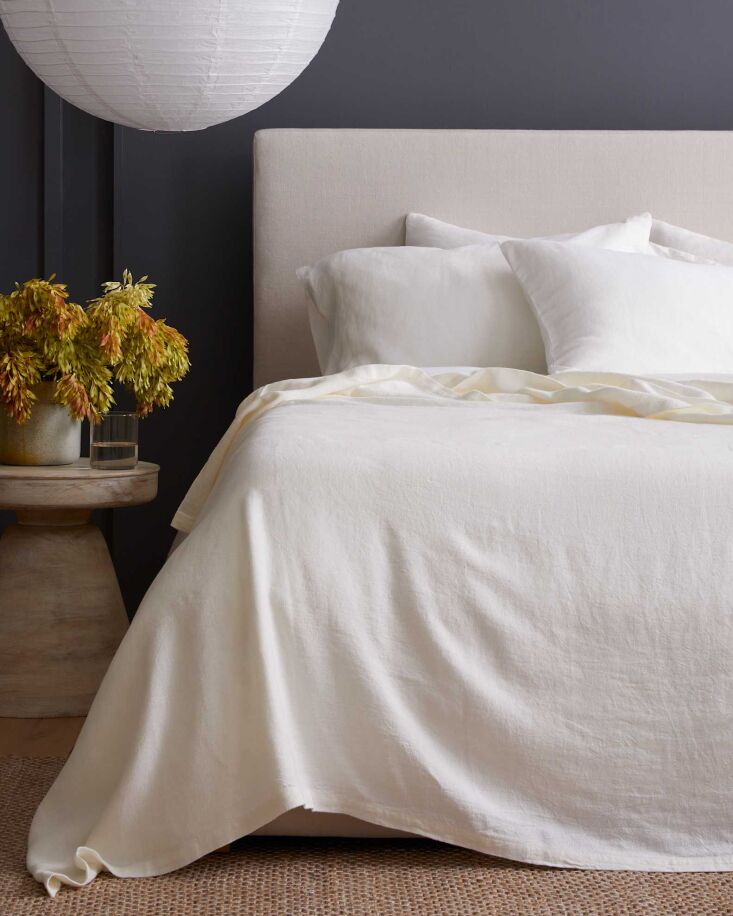 An ivory-colored linen bed cover neatly folded on a bed.