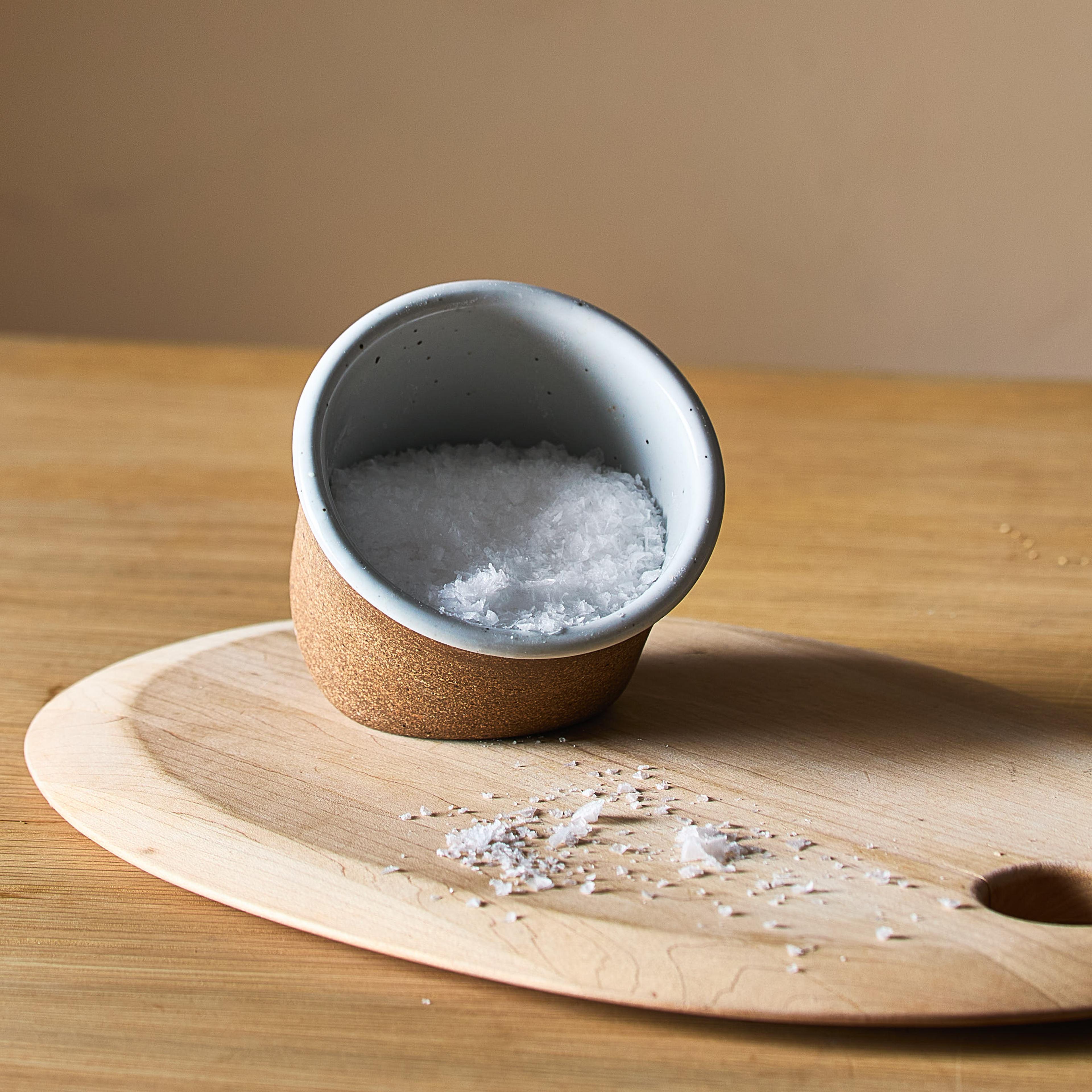 A small stone salt cellar filled with coarse sea salt.