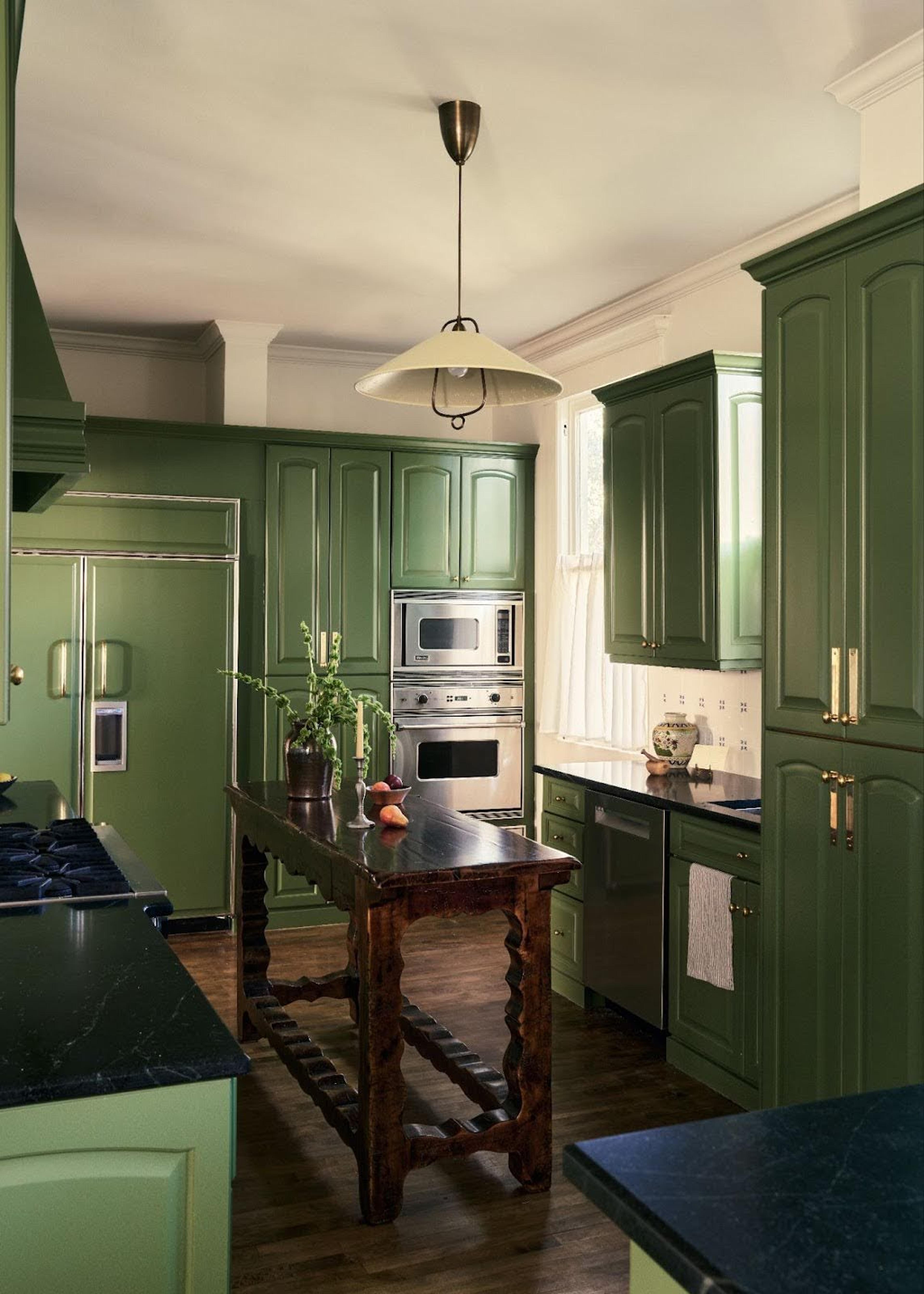 A kitchen featuring sophisticated dark green cabinets and elegant hardware.