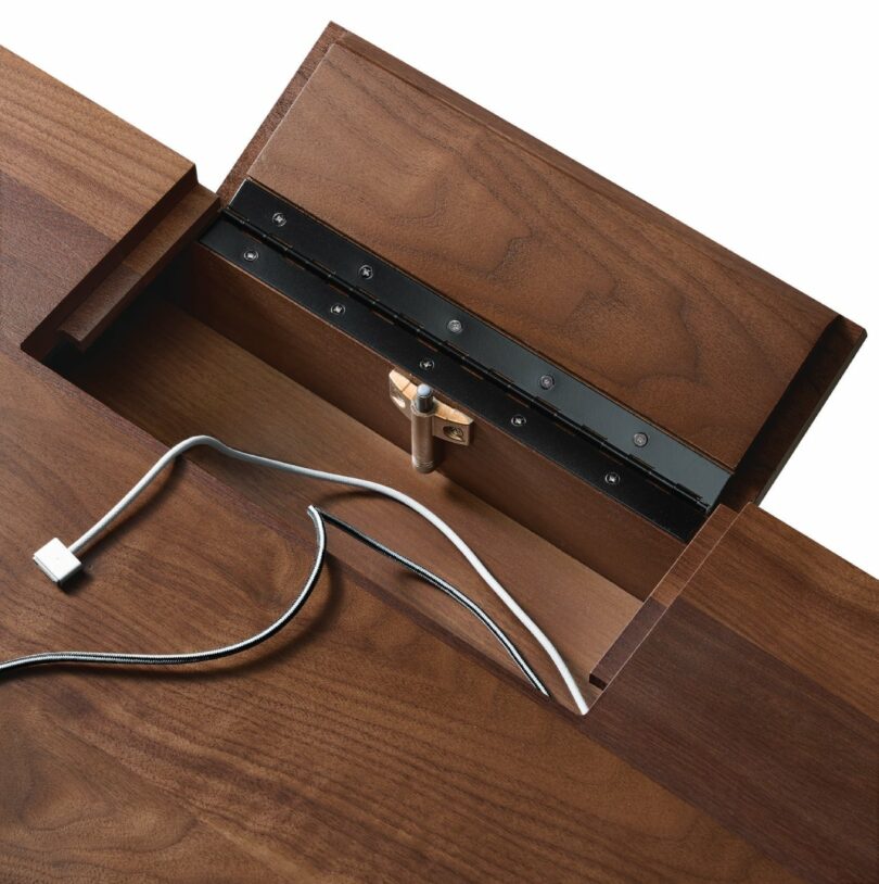 Close-up of the desk's rear hinged hatch open to show integrated cable routing and USB connectivity.