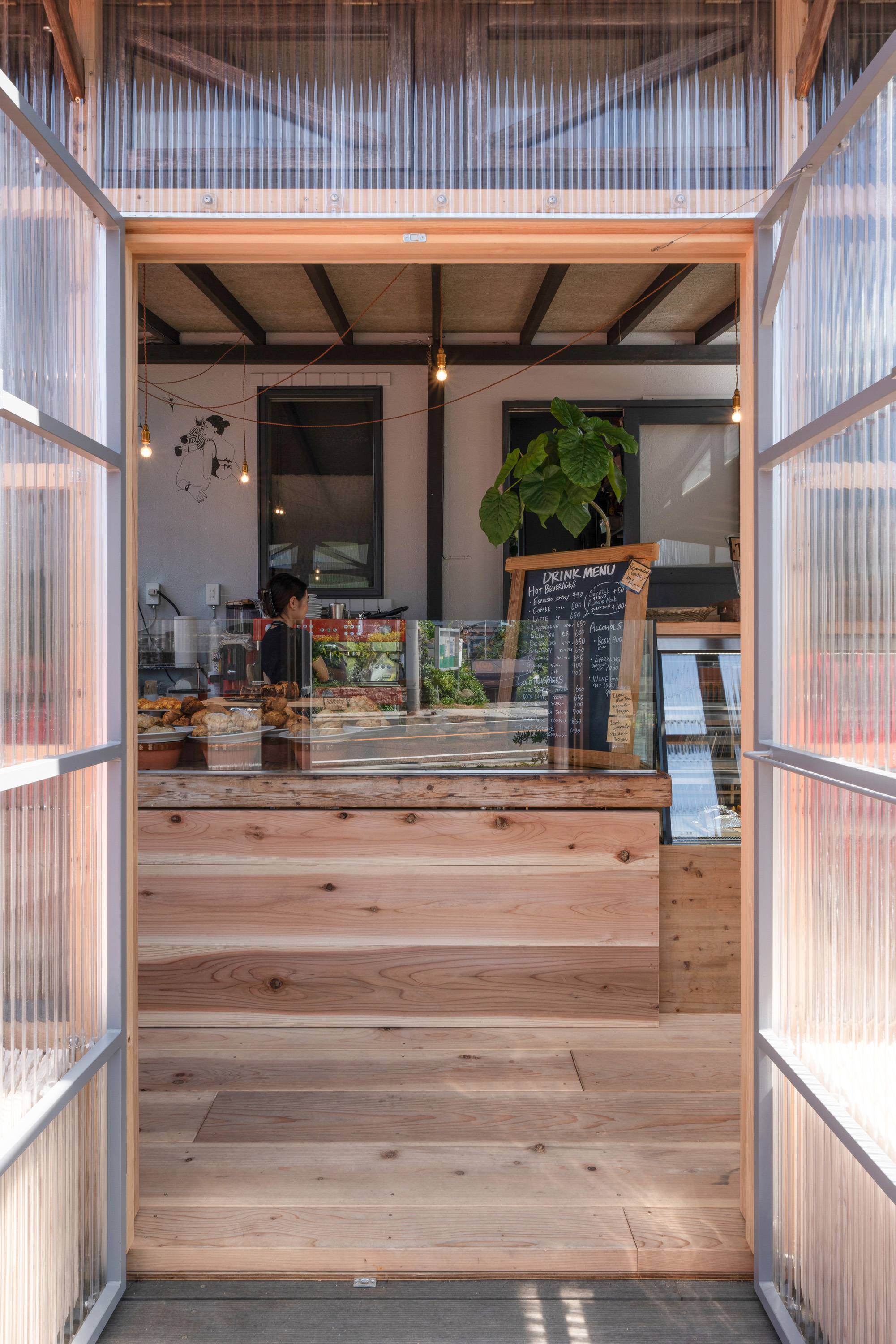 Soft light filtering through translucent polycarbonate walls onto a wooden café counter.