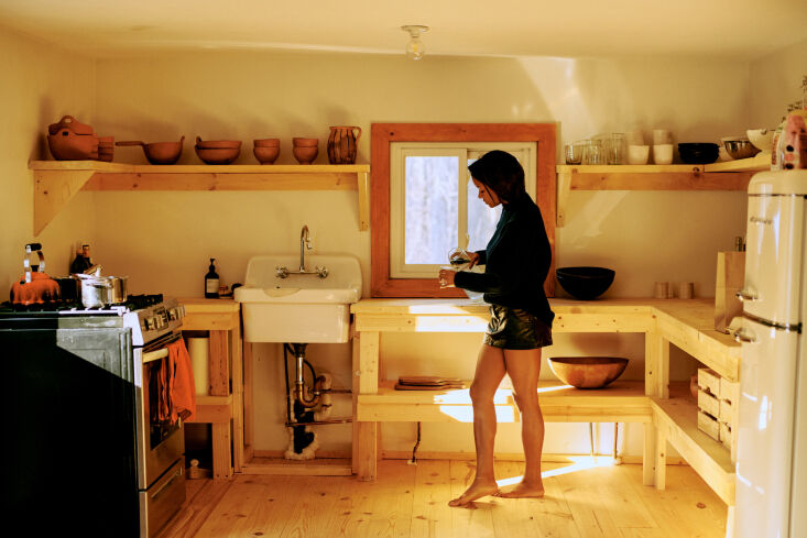 A minimalist kitchen with open shelving and simple ceramic light fixtures.