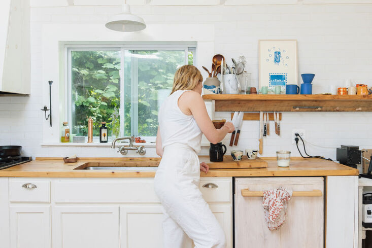 An airy eat-in kitchen featuring white walls and a complete absence of upper cabinets.