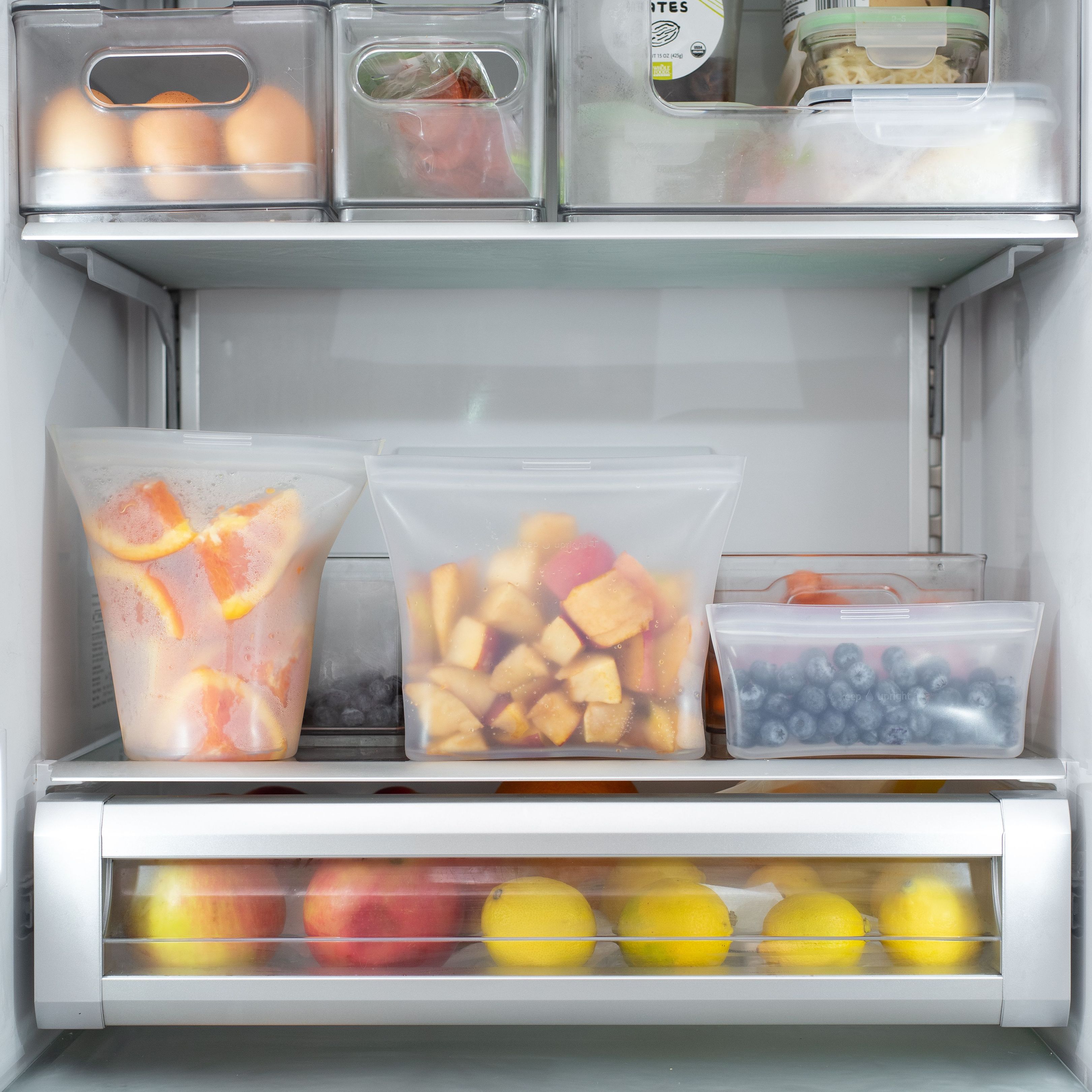 A collection of clear stackable bins and organization tools used for refrigerator efficiency.