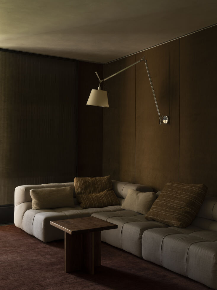 A cozy 'Snug Room' with velvet wall paneling, a plush sofa, and soft lighting.