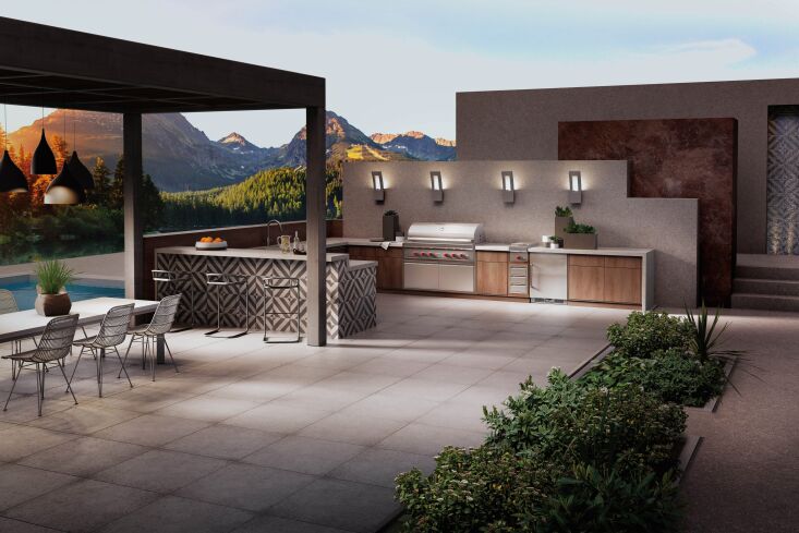Night view of an outdoor kitchen illuminated by warm under-counter LED strips and task lighting.