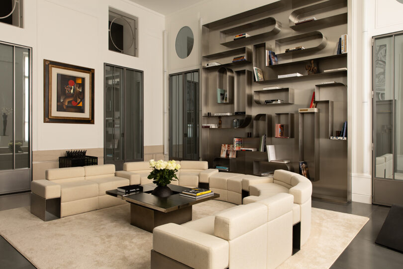 A modern living room with cream modular sofas and a geometric metal bookshelf filled with books.