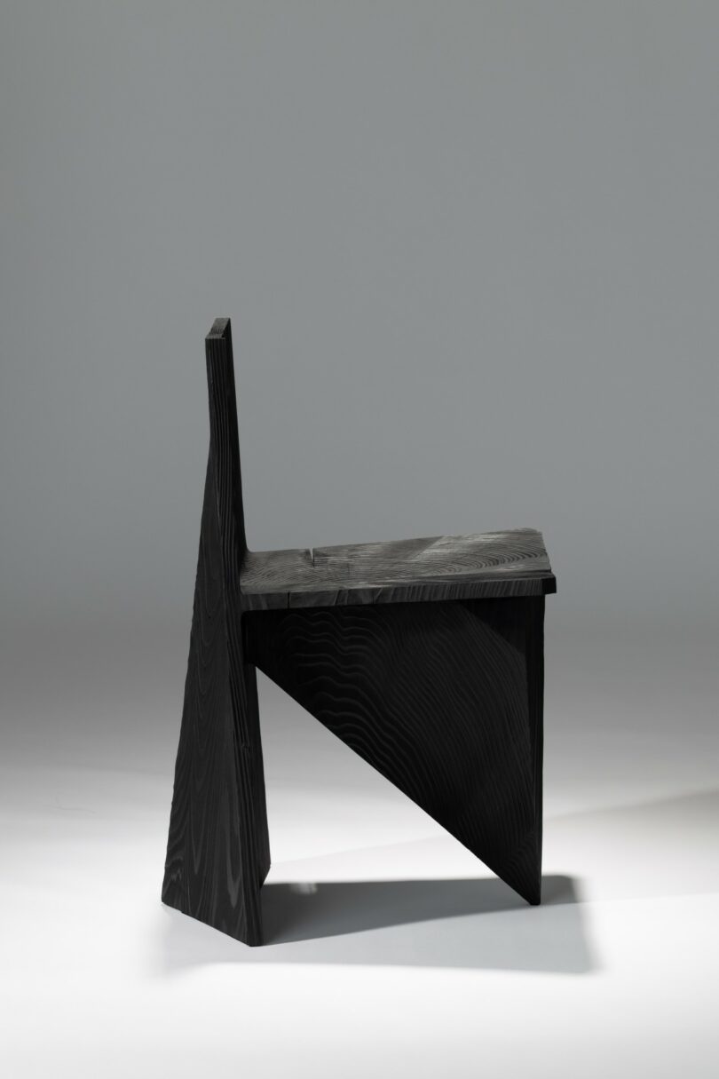 Modern geometric wooden chair with a black finish against a light gray background.