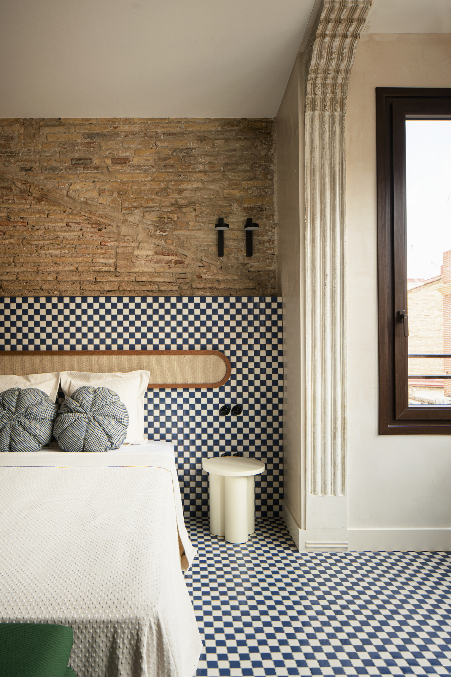 Bedroom with high ceilings, exposed original brick, and decorative white ceiling moldings.
