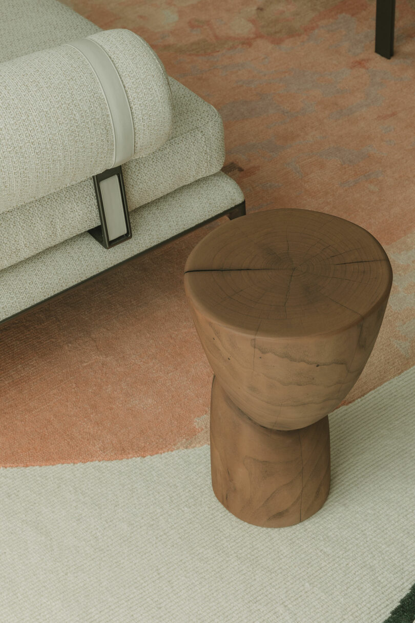 A close-up of a textured white sofa with a leather detail next to a wooden stool.