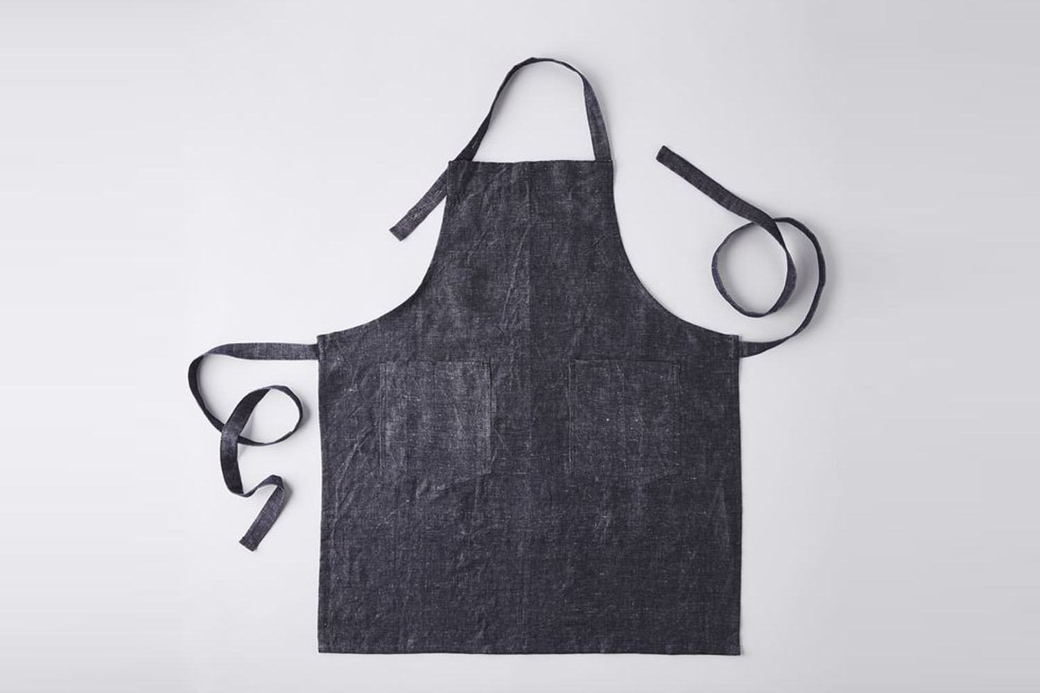 A light linen-cotton blend apron with adjustable neck and waist ties.