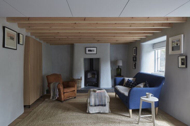 A living room hearth with a wood-burning stove and curved walls finished in gray Tadelakt lime plaster.