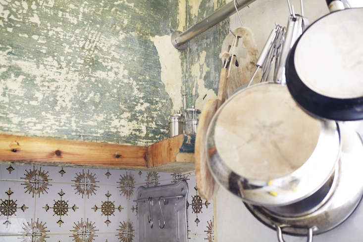 Close-up of a kitchen wall with layers of white and original blue-toned paint revealed.