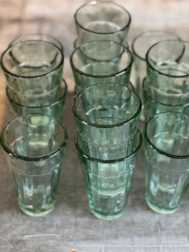 A sequence of delicate glassware in watery shades of clear and pale green arranged down a table.
