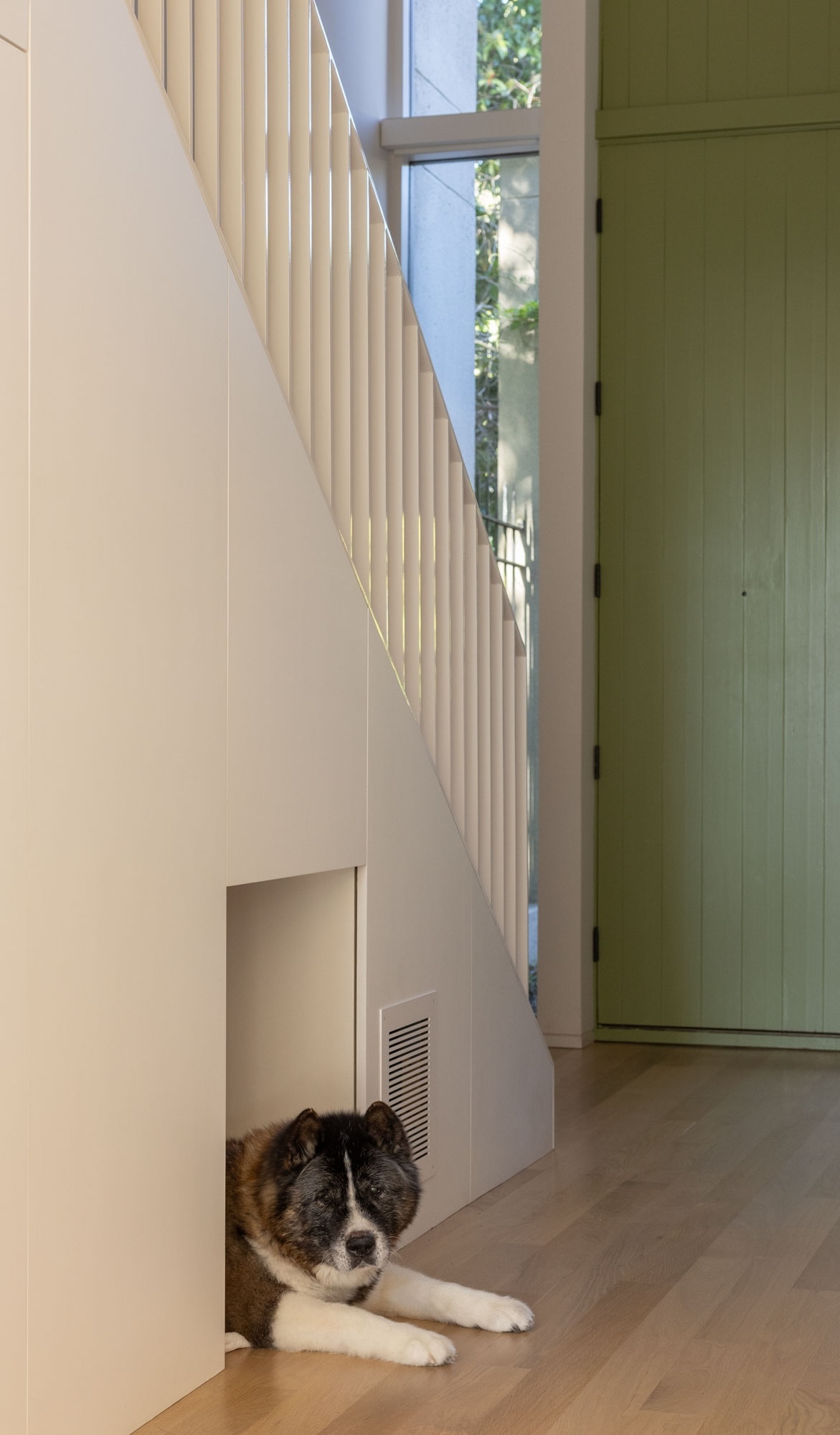 A wooden staircase with a built-in alcove underneath containing a dog bed.
