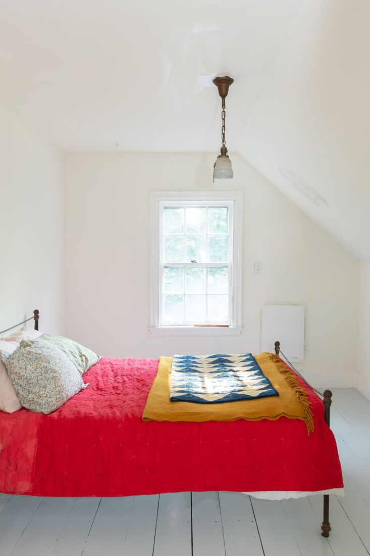 A bright red quilt spread over a bed in a minimalist bedroom.
