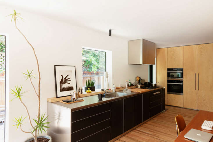 A minimalist kitchen area featuring a compact dishwasher and integrated stainless steel housing.