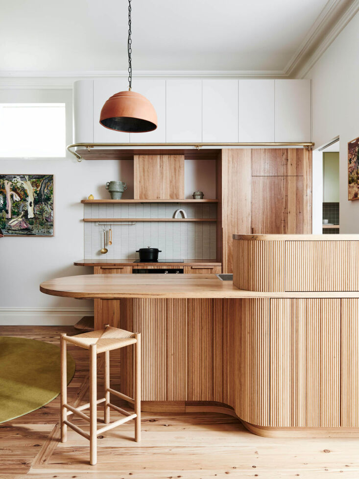 A wide shot of the completed Melbourne kitchen featuring undulating wood and high ceilings.