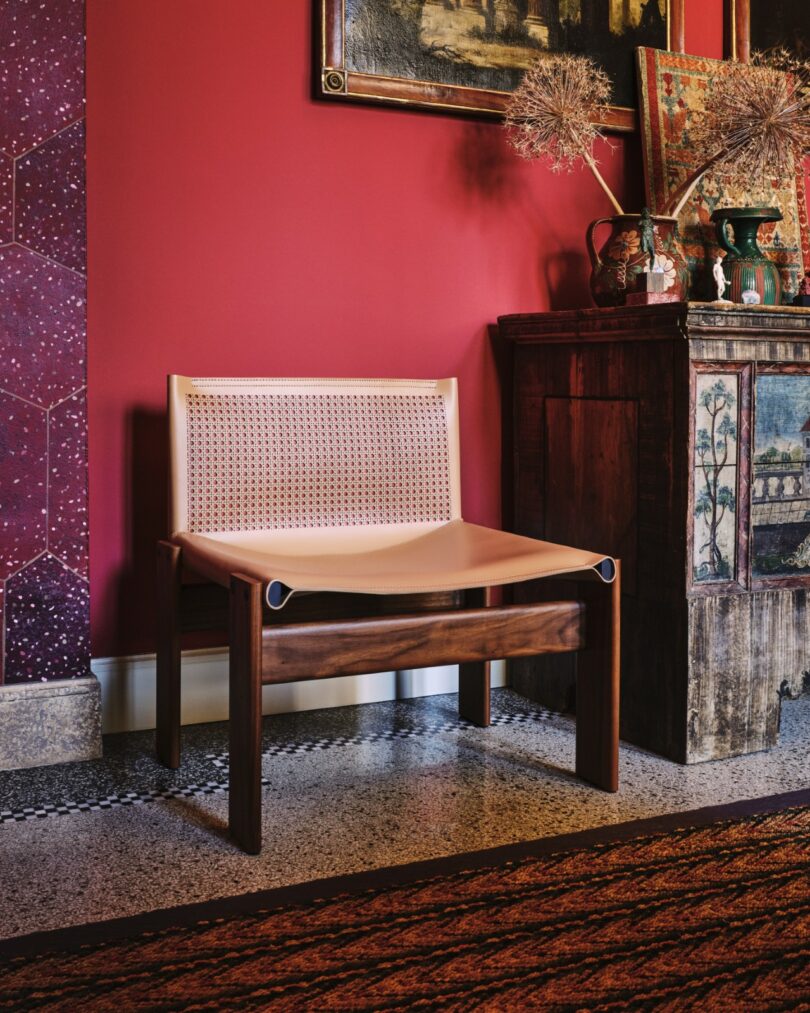 The Monk chair in a vibrant red room setting next to a vintage cabinet.