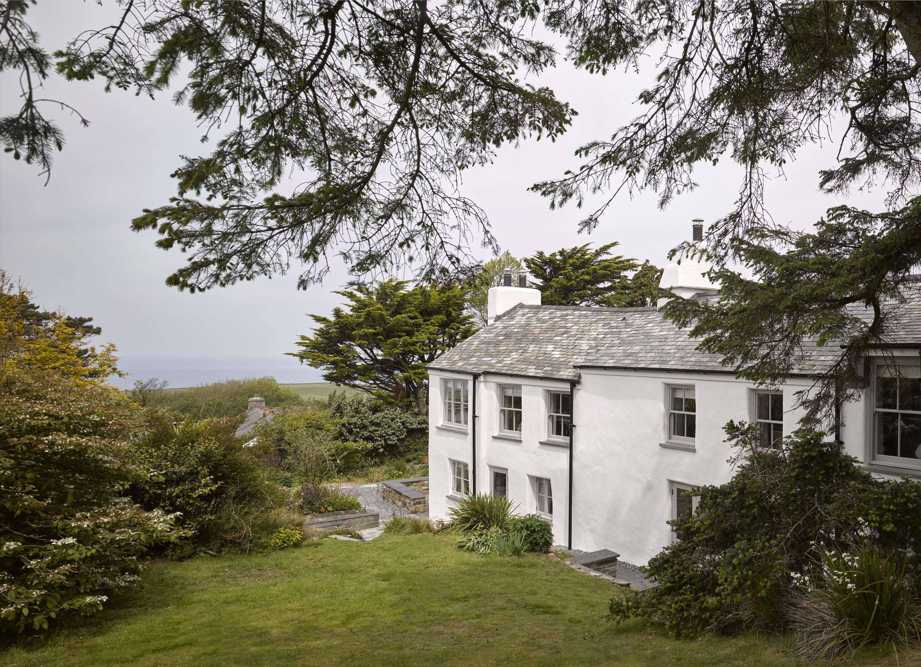 Exterior view of the updated longhouse by Tuckey Design Studio showing the blend of historic stonework and modern additions.