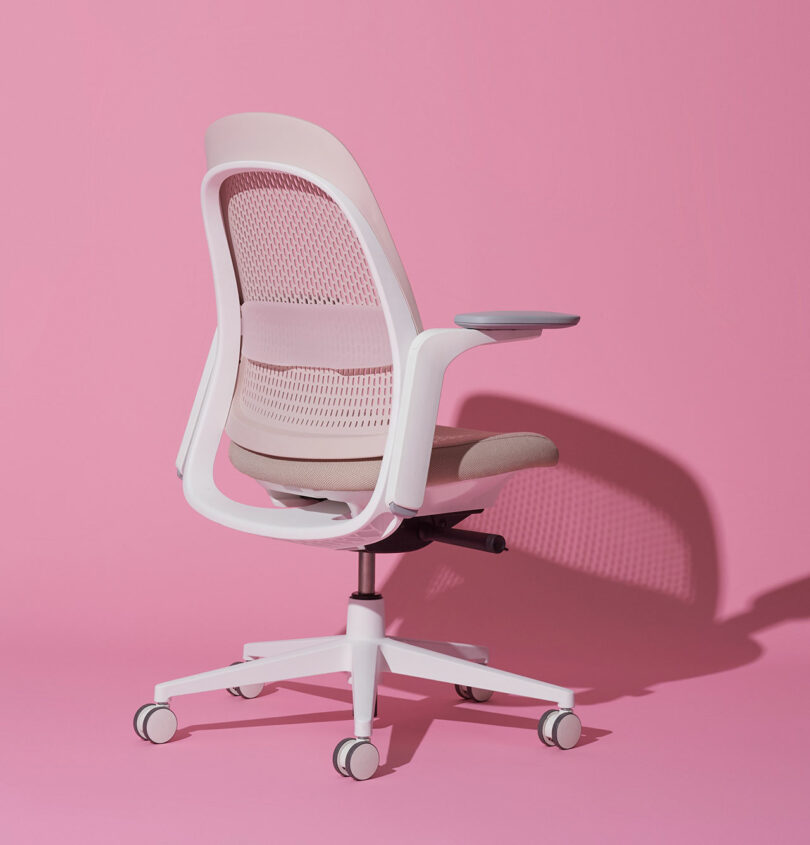 Profile view of a modern office chair with pink background highlighting the adjustable armrests and seat.