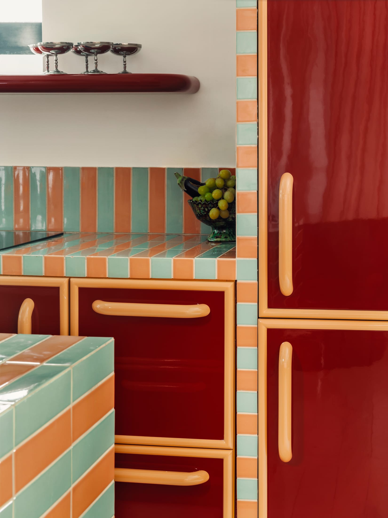 A kitchen area featuring high-gloss coral finishes and contrasting deep-toned walls.
