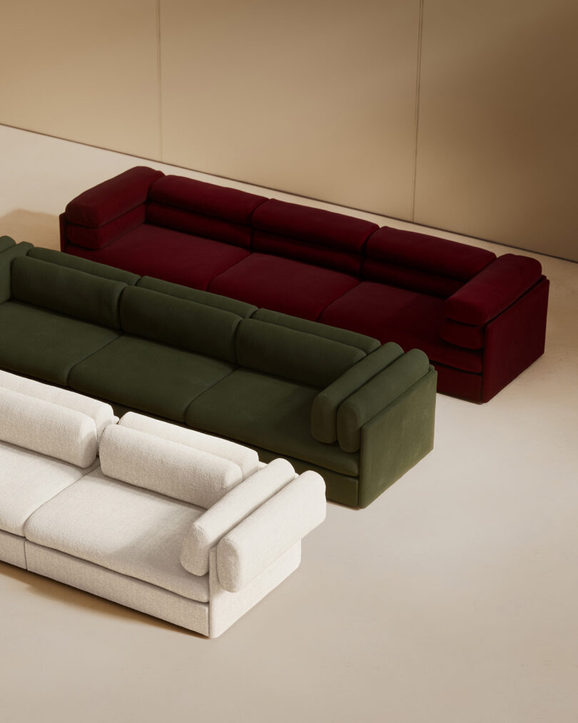 Three modular Elogio sofas in white, olive green, and dark red arranged in a staggered formation.