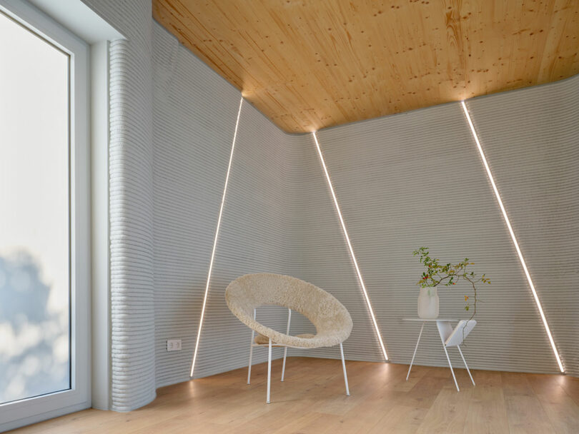 Minimalist interior room with textured gray 3D-printed walls and integrated diagonal LED light strips.