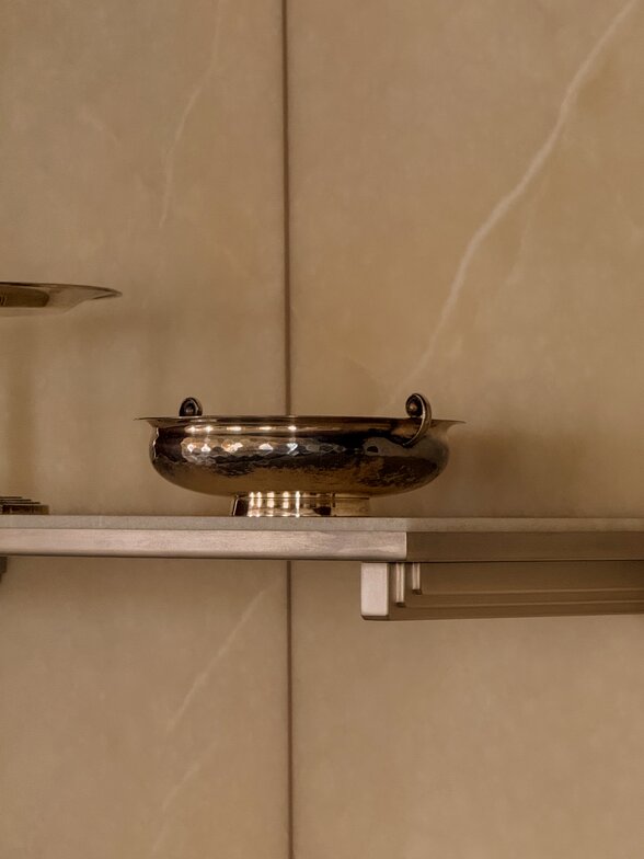 Close-up of styled open shelving in the kitchen with ceramic vessels and decorative objects.