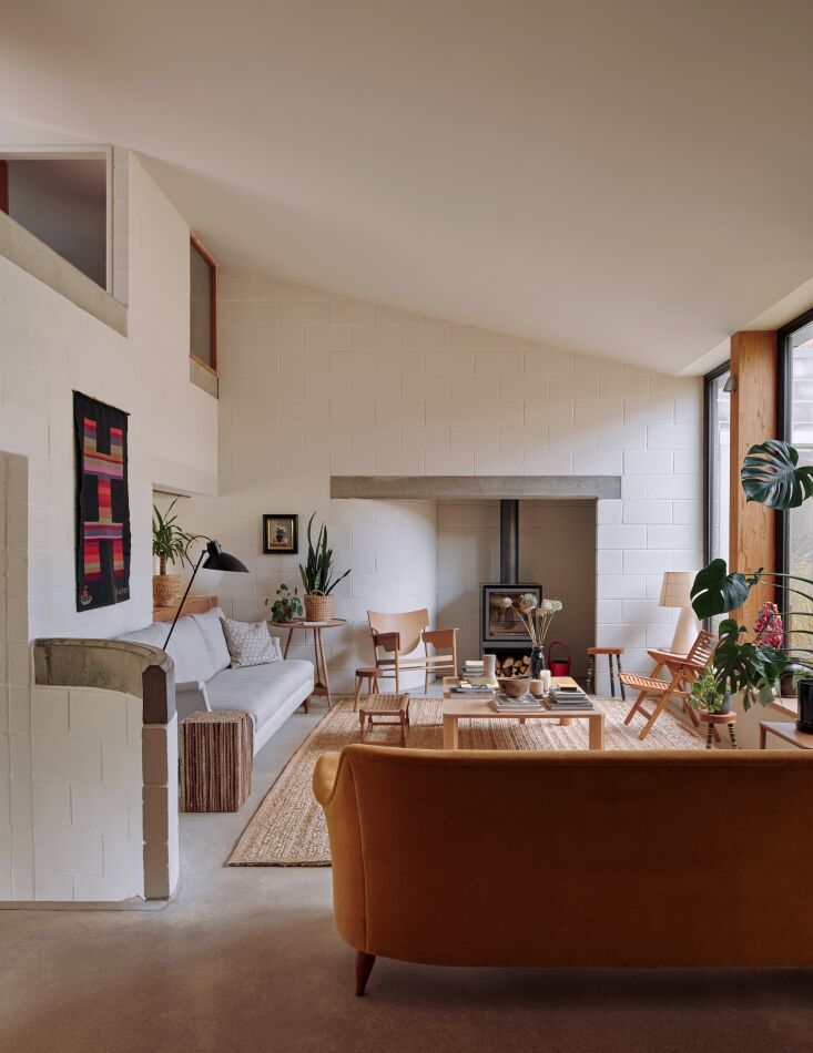 Double-height living room with painted cinderblock walls and a large inglenook fireplace.