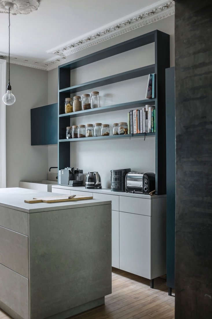 A vertical coffee and tea station painted in Hague Blue with neatly organized appliances and jars.