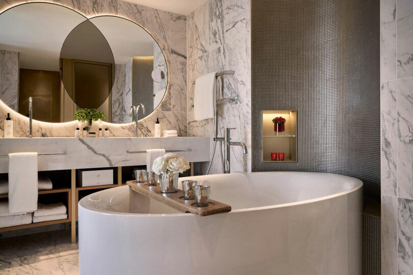 Luxury bathroom with a freestanding tub, marble walls, and large mirrors.