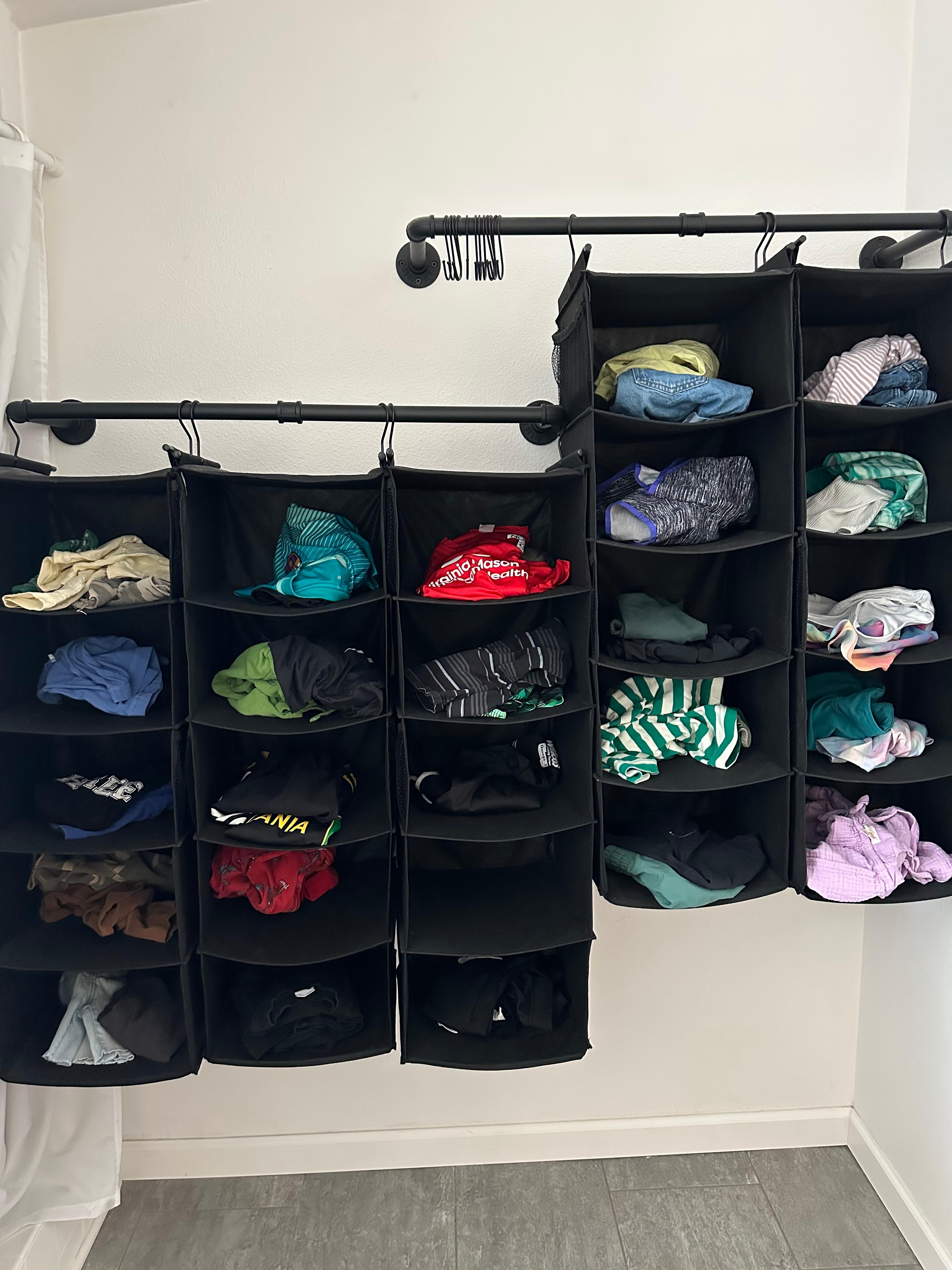 A fully stocked hanging organizer with colorful children's clothes inside a closet.