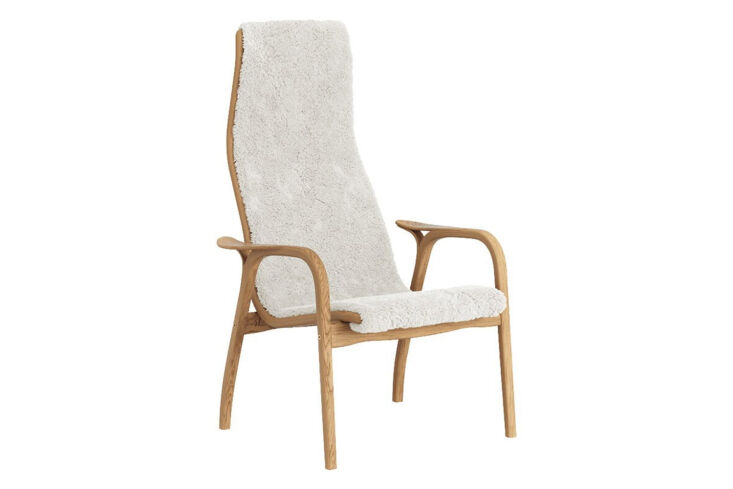Swedese Lamino Easy Chair with a light wooden frame and curly white sheepskin.