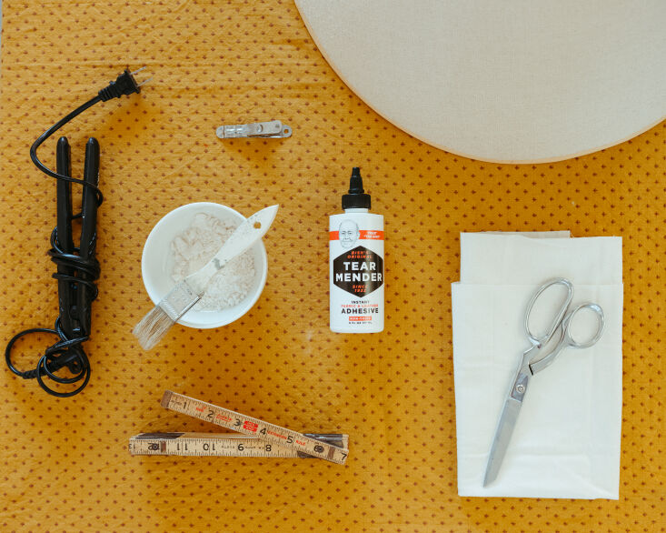 Flat lay of DIY materials including white fabric, scissors, and measuring tools.