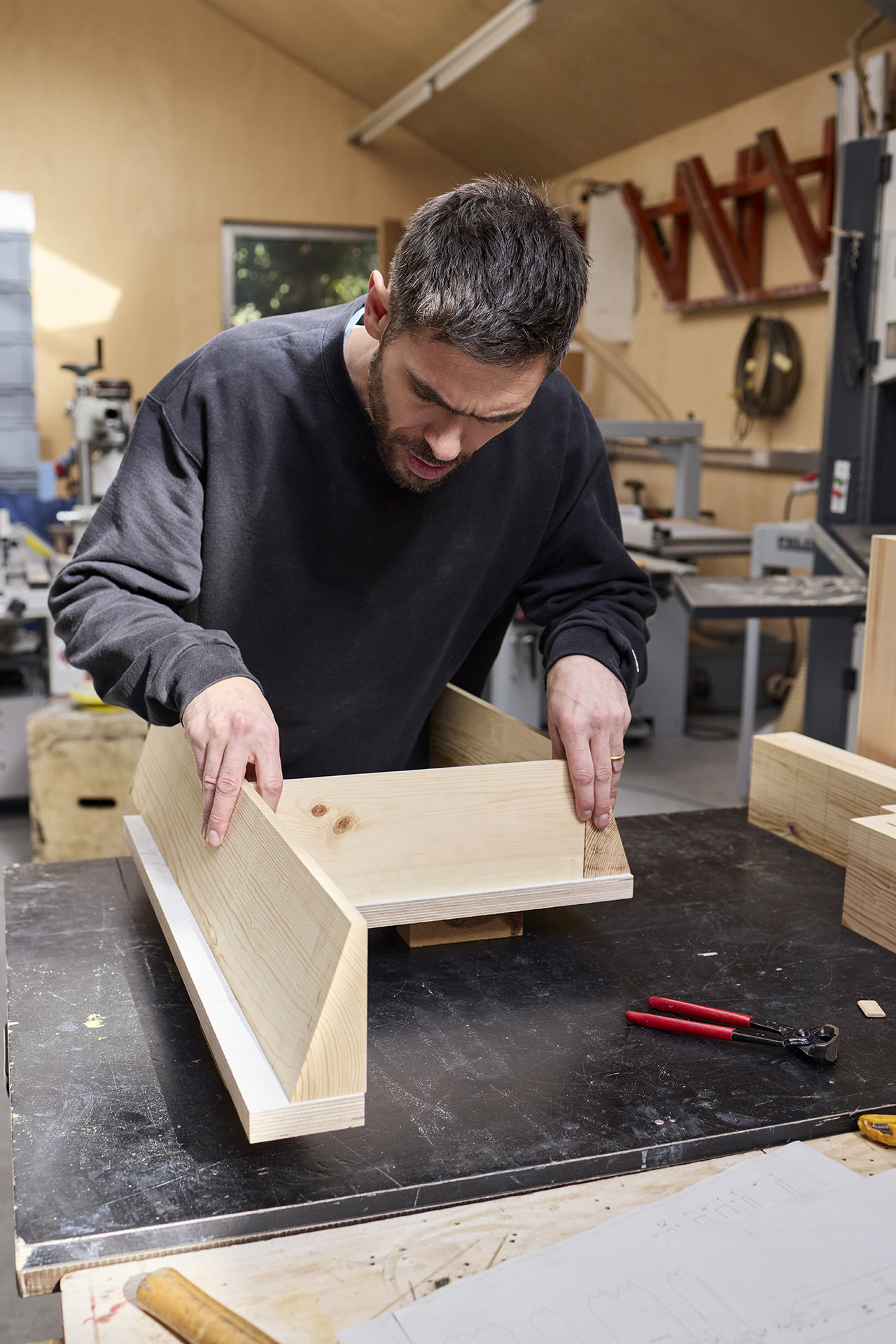 Max Lamb in his workshop aligning wooden components for assembly.