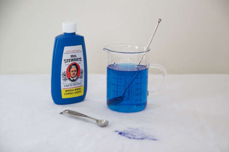Blue laundry liquid being measured in a glass beaker.