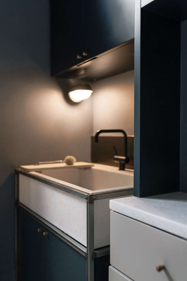 A custom white blanco marble sink set in a welded steel stand with a matte black Vola faucet.