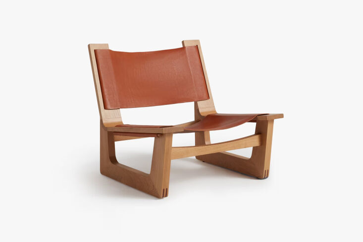 The Parachute Leather Sling Chair in tan leather and oak, inspired by mid-century Danish design.