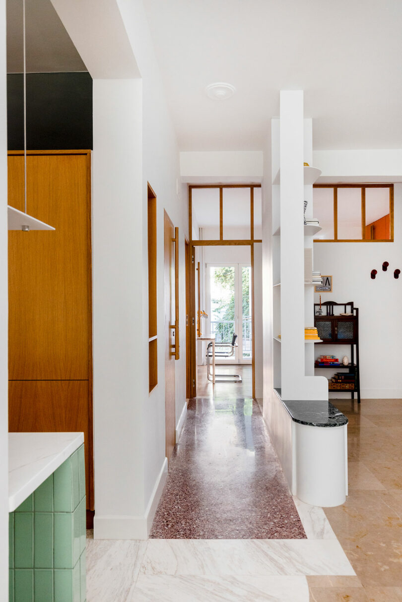 A modern hallway with polished marble floors, white walls, and a minimalist white metal shelving unit.