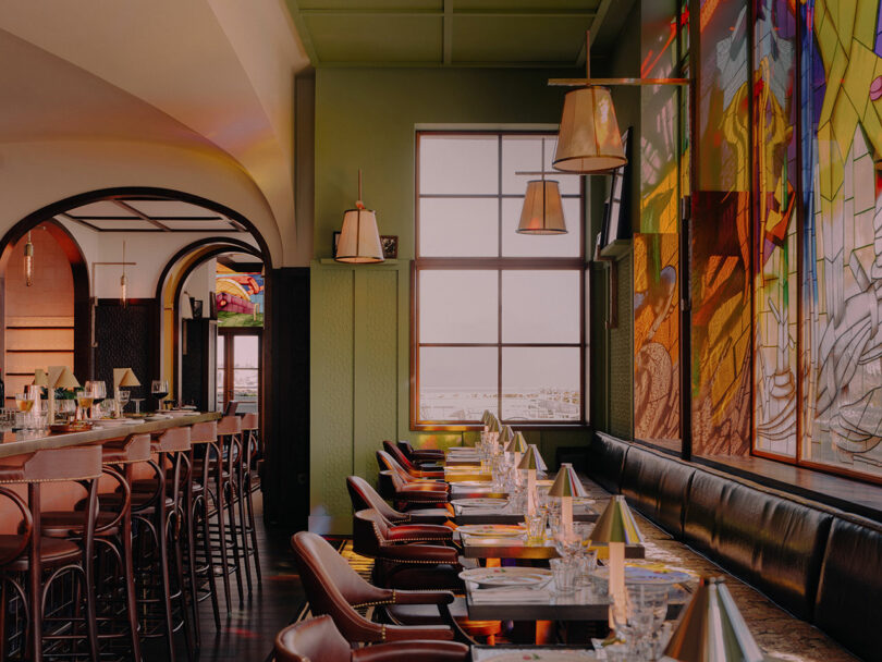 Modern restaurant interior with leather chairs and colorful stained glass art on the walls.