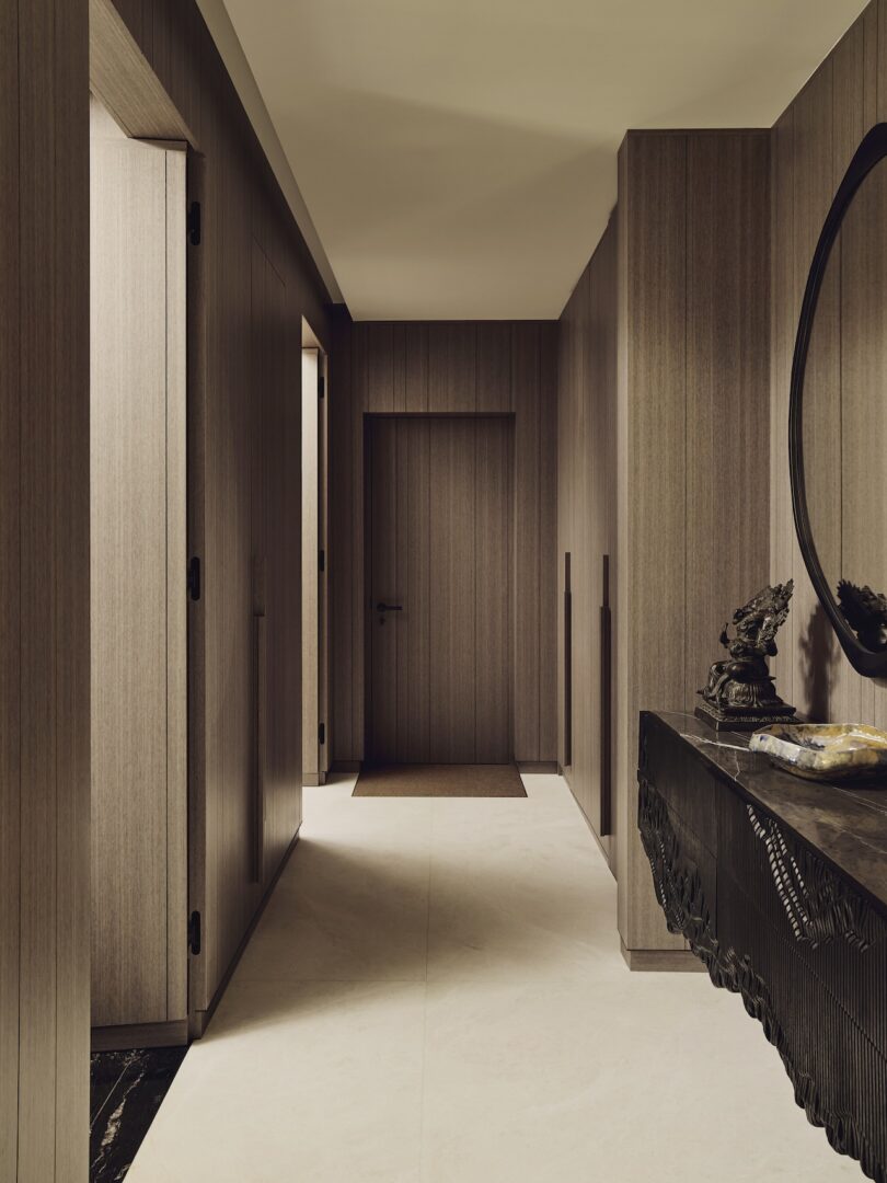A modern hallway with horizontal wood-paneled walls and a minimalist dark console table.