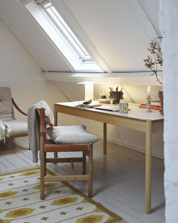 A bright attic home office with desk and natural light coming from roof windows.