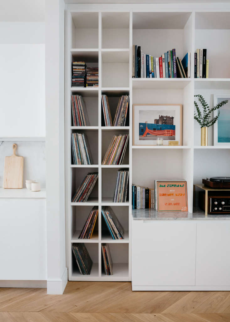 Large custom wooden built-in shelving housing a mix of vinyl records and CDs.