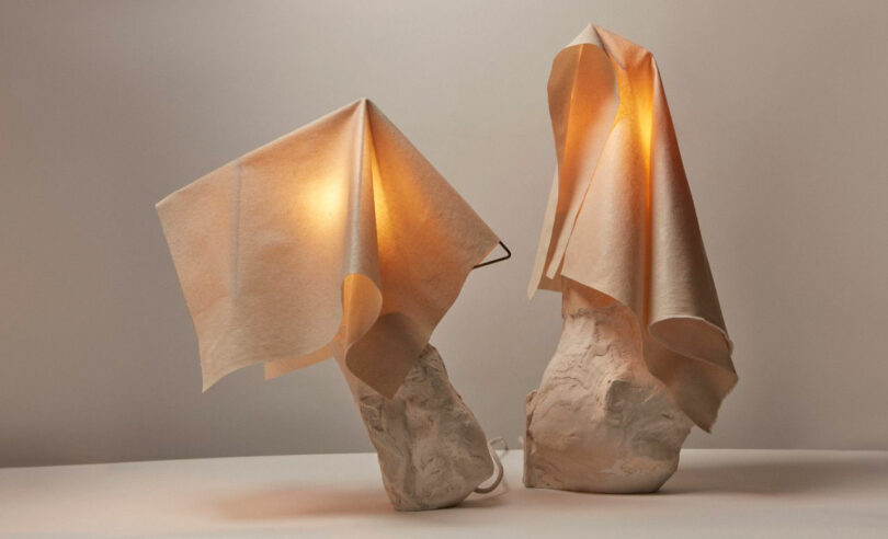 Two sculptural white table lamps with fabric drapes and textured bases.