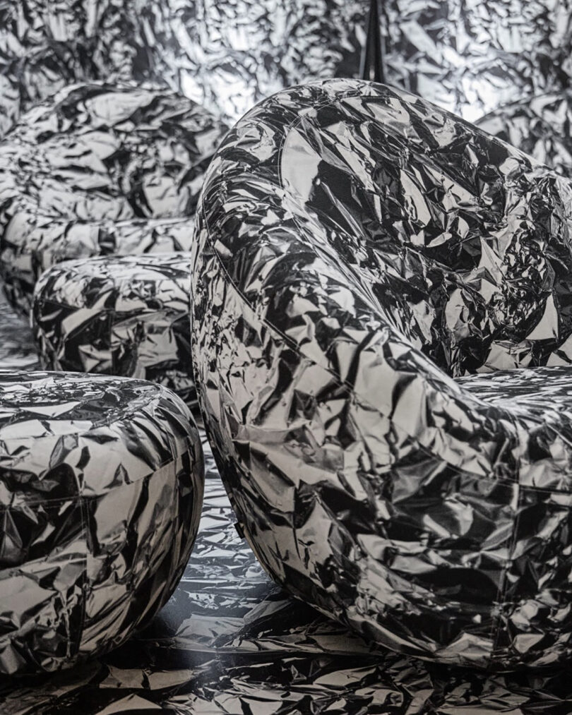 Monochrome close-up of rounded chairs and ottomans featuring a high-contrast black and white crumpled pattern.
