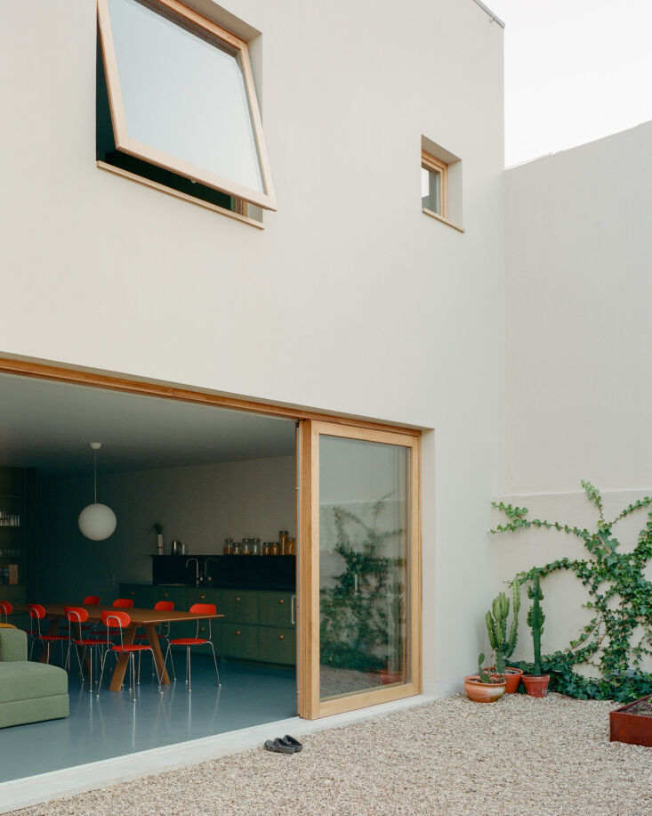 A modern two-story glass facade with sliding doors overlooking a private courtyard.